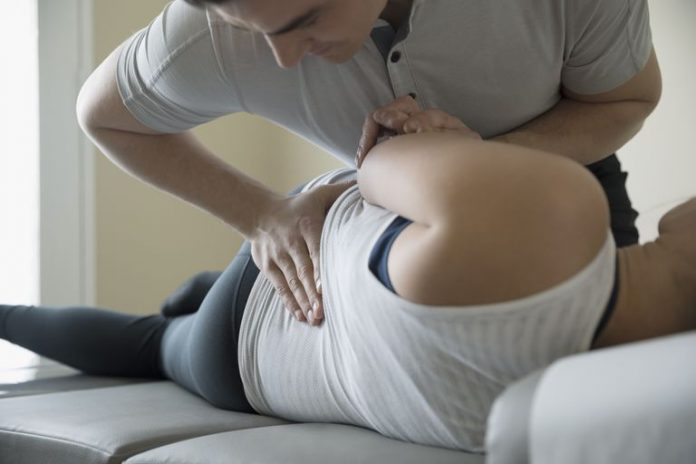 5e1f73ebfbdfd4b5606c6a95_male-chiropractor-adjusting-woman-on-clinic-examination-table-728755913-5b5cae27c9e77c002cbd85e7-696x464