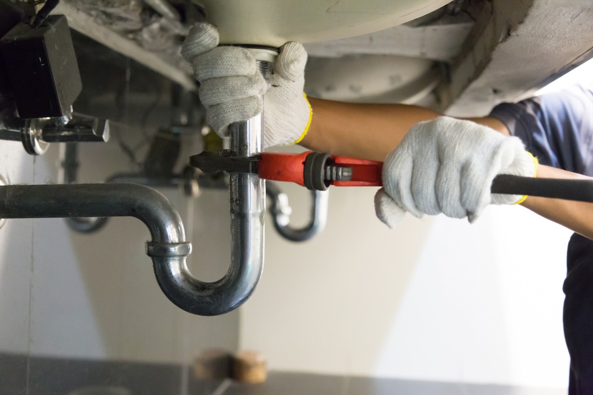 plumber-fixing-white-sink-pipe-with-adjustable-wrench-picture-id1150199946