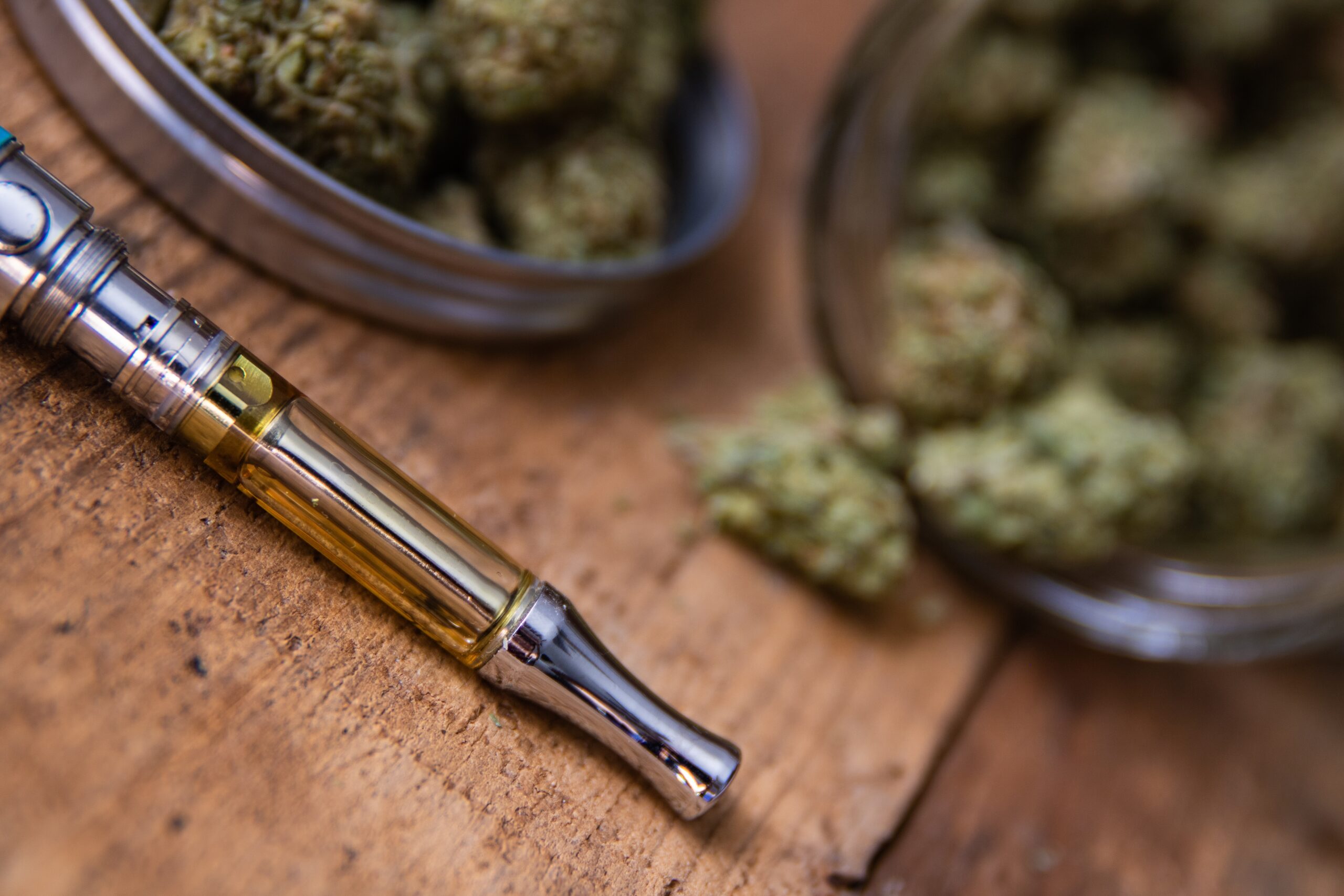 Cannabis Oil Vape Pen & Marijuana Buds In Open Glass Jar In Background